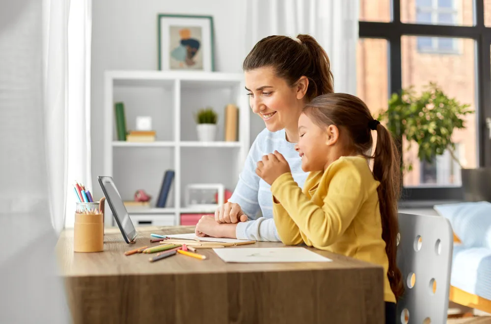 A mother and her daughter looking at a tablet together at a desk